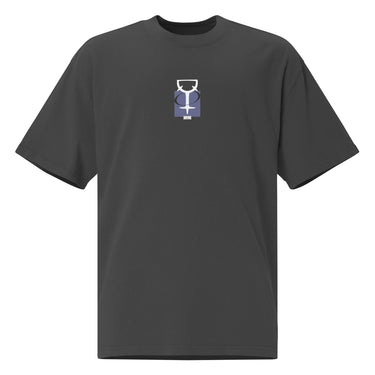 The front of a faded black oversized t-shirt. Centered on the chest is a small graphic featuring a stylized white symbol, resembling a chalice, set against a blue rectangular background.