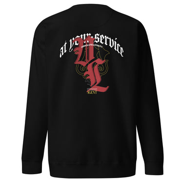 Back view of a solid-colored sweatshirt. A large, ornate graphic on the upper back features the text "at your service" arched over a large, high-contrast gothic monogram. The design is embellished with fine-line scrollwork and 3d lettering of V and L in blackletter font.