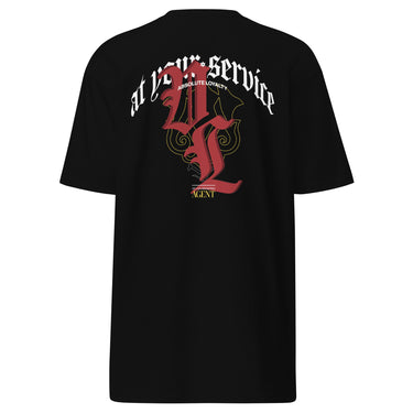 Back view of a solid-colored shirt. A large, ornate graphic on the upper back features the text "at your service" arched over a large, high-contrast gothic monogram. The design is embellished with fine-line scrollwork and 3d lettering of V and L in blackletter font.