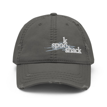 Front view of an distressed hat in white. It features an embroidered logo with the words "spook shack" in a stylized, stacked font, layered over abstract horizontal brush strokes.