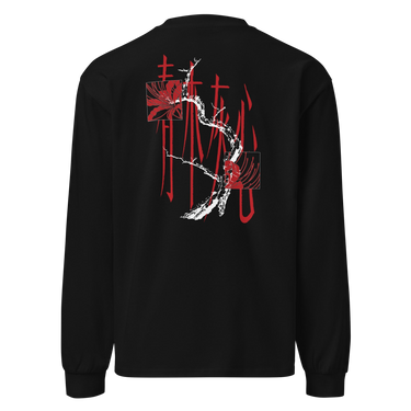 Back view of a longsleeve in black. Four large vermillion brushstroke characters reading "春木灰心" run vertically down the center, layered with a stark white-and-red painterly tree branch winding through them. Two crimson rectangles bracket smaller ink motifs in the upper-left and lower-right, giving the composition an expressive, calligraphic, graphic-forward feel.