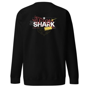 Back view of a solid-colored sweatshirt. A large, chaotic collage graphic on the upper back features the word "SHARK" in a bold font. The design is layered with various handwritten signatures, sketchy scribbles, and abstract background patterns.