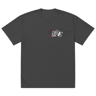 Front view of a solid-colored oversized-tee. A small collage graphic on the left chest features the letters 'J' and 'E' and a serpent-like ampersand, layered over abstract shapes and sketchy lines that seemingly cover the letters ‘A’ and ‘N’ to form “Jane”.
