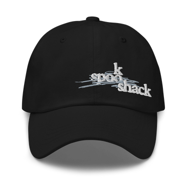 Front view of an baseball cap in black. It features an embroidered logo with the words "spook shack" in a stylized, stacked font, layered over abstract horizontal brush strokes.