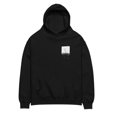 Front view of an oversized hoodie in black. A small halftoned panel sits on the left chest: a bare, leafless tree standing over dark undergrowth, printed with a woven fabric texture and rough torn edges. Below it the words "pas seul" are set in a fine serif, the letters scattered and stepping down to the right.