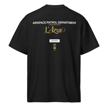 Back view of a box tee in Black. A stacked graphic fills the upper back: "AIRSPACE PATROL DEPARTMENT" in heavy white capitals, "GLORIA NOS DUCIT" in smaller gold capitals beneath it, then "L'Azur" in a large gold script with a long trailing flourish. Below sit a small white box lettered "FIRST SPEAR" in black, a weathered gold seal stamp carrying two characters, and "gen 5" in gold.
