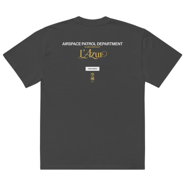 Back view of an oversized tee in Faded Black. A stacked graphic fills the upper back: "AIRSPACE PATROL DEPARTMENT" in heavy white capitals, "GLORIA NOS DUCIT" in smaller gold capitals beneath it, then "L'Azur" in a large gold script with a long trailing flourish. Below sit a small white box lettered "FIRST SPEAR" in black, a weathered gold seal stamp carrying two characters, and "gen 5" in gold.