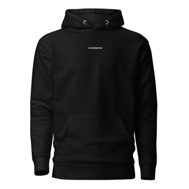 Front view of an hoodie in black. Minimal design featuring a small white lowercase word “constance” centered across the upper chest. The typography is clean and modern, standing out subtly against the solid black fabric.