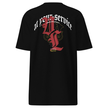 Back view of a solid-colored shirt. A large, ornate graphic on the upper back features the text "at your service" arched over a large, high-contrast gothic monogram. The design is embellished with fine-line scrollwork and 3d lettering of V and L in blackletter font.