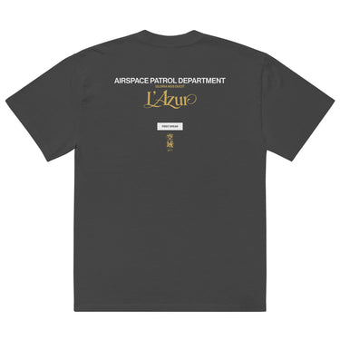 Back view of an oversized tee in Faded Black. A stacked graphic fills the upper back: "AIRSPACE PATROL DEPARTMENT" in heavy white capitals, "GLORIA NOS DUCIT" in smaller gold capitals beneath it, then "L'Azur" in a large gold script with a long trailing flourish. Below sit a small white box lettered "FIRST SPEAR" in black, a weathered gold seal stamp carrying two characters, and "gen 5" in gold.