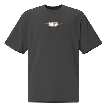 Front view of a Oversized Tee in Faded Black. a small chest graphic pairing a gold cursive wordmark partially overlaid by a bold white stylized emblem, with a block-letter word underneath in the same gold tone