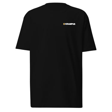 Front view of an t-shirt in black. A minimalist design is placed on the upper left chest, featuring a compact arrangement of graphic elements. The word “KRAMPUS” appears in small white uppercase lettering, paired with a circular gold icon to its left.