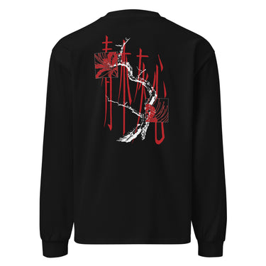 Back view of a longsleeve in black. Four large vermillion brushstroke characters reading "春木灰心" run vertically down the center, layered with a stark white-and-red painterly tree branch winding through them. Two crimson rectangles bracket smaller ink motifs in the upper-left and lower-right, giving the composition an expressive, calligraphic, graphic-forward feel.