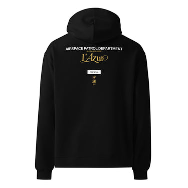 Back view of an oversized hoodie in Black. A stacked graphic fills the upper back: "AIRSPACE PATROL DEPARTMENT" in heavy white capitals, "GLORIA NOS DUCIT" in smaller gold capitals beneath it, then "L'Azur" in a large gold script with a long trailing flourish. Below sit a small white box lettered "FIRST SPEAR" in black, a weathered gold seal stamp carrying two characters, and "gen 5" in gold.