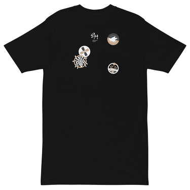 Front view of a solid-colored shirt. The chest features a small signature and four different circular emblems, each containing a unique high-contrast, abstract pattern.