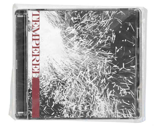 CD jewel case in clear shrink wrap. The cover is a black and white photograph of a dense burst of white sparks, with the word TEMPERED running vertically down the left edge in deep red stencil type above a deep red bar.