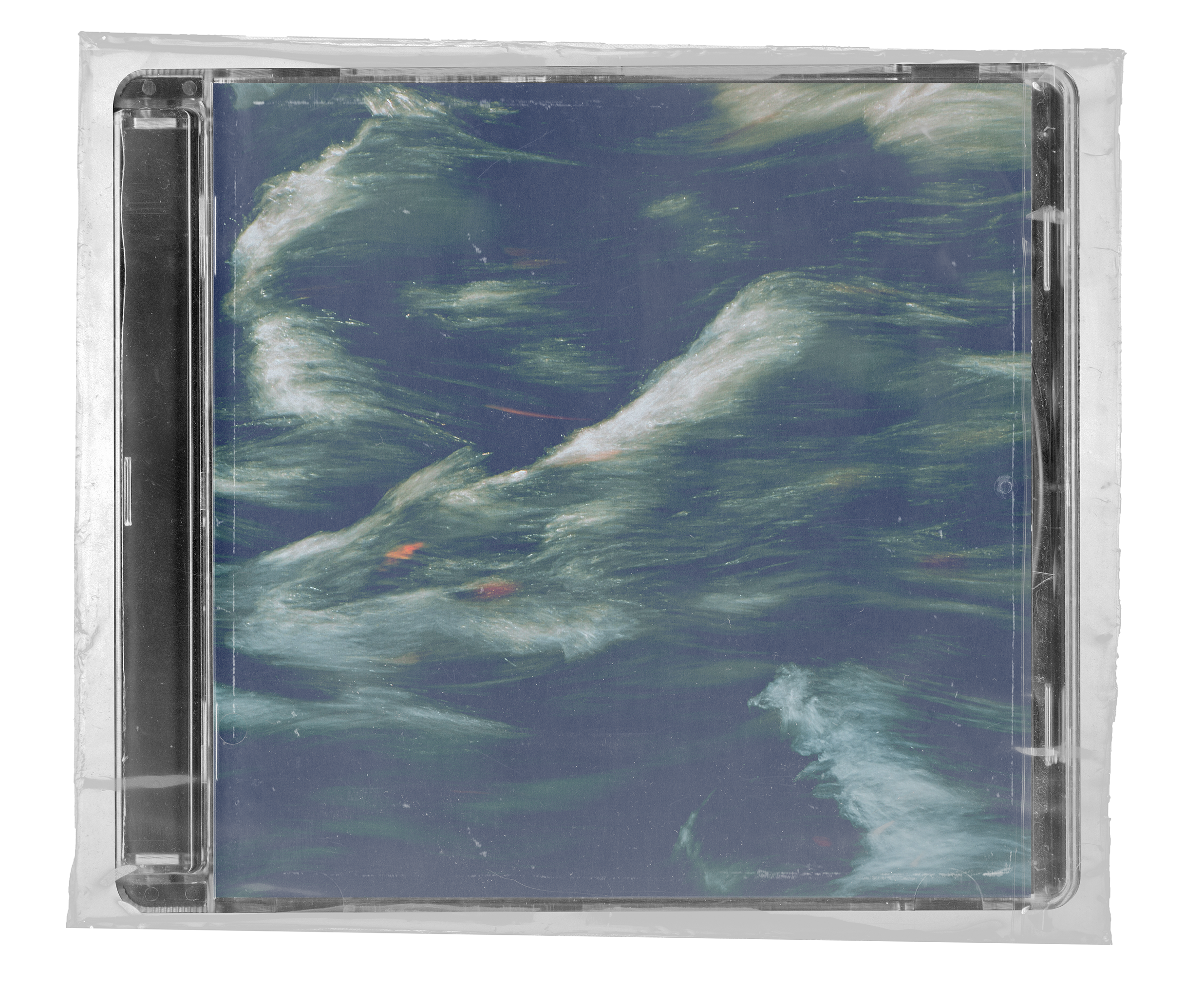  A top-down shot of a CD in a clear jewel case, still sealed in plastic wrap. The CD's cover art is a photograph of large, dark blue waves with white foam crests, captured with a long exposure to create a blurry, streaky effect. 