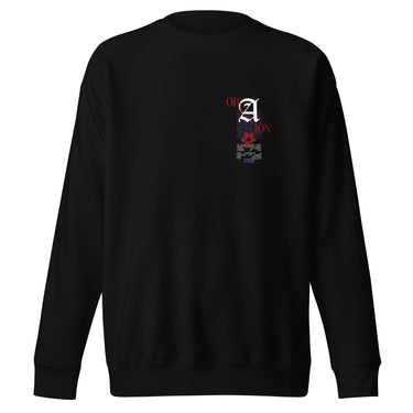 Front view of a solid-colored sweatshirt. A small, vertical collage graphic on the left chest features a large, high-contrast gothic letter 'A' layered with multiple small blocks of text and a floral illustration.