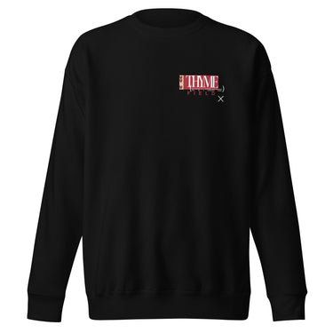 A black crewneck sweatshirt with an off centered graphic to the left side of the sweatshirt. The design features the word 'THYME' in a large, white font layered over a red rectangle accompanied by red text depicting "FIELD" underneath it.