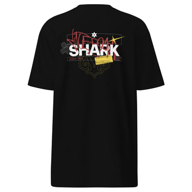 Back view of a solid-colored shirt. A large, chaotic collage graphic on the upper back features the word "SHARK" in a bold font. The design is layered with various handwritten signatures, sketchy scribbles, and abstract background patterns.