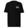Front view of a solid-colored shirt. A small collage graphic on the left chest features the letters 'J' and 'E' and a serpent-like ampersand, layered over abstract shapes and sketchy lines that seemingly cover the letters ‘A’ and ‘N’ to form “Jane”.