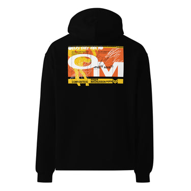 Black oversized hoodie, back view, showcasing a large abstract graphic in orange, yellow, black, and white. The design includes bold typography, Japanese characters, geometric shapes, and layered text overlaid with dynamic line art and circular motifs.