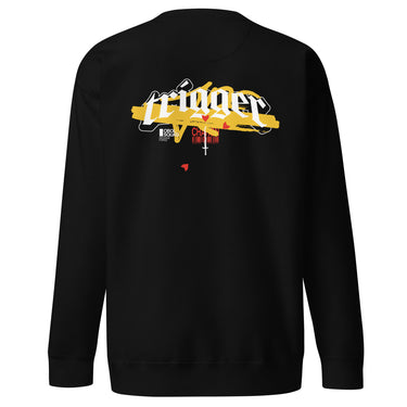 Back view of a solid-colored, sweatshirt. A large, horizontal graphic on the upper back features the word "trigger" in a high-contrast, graffiti, streetwear-style font. This is layered over a wide brushstroke shape and several smaller text elements, including a barcode and a cross symbol.