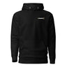 Front view of an hoodie in black. A minimalist design placed on the upper left chest shows a compact arrangement of small graphic elements, including a circular icon, the word “KRAMPUS” in bold, and a narrow vertical block with stylized symbols.