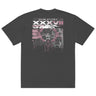 Back view of an oversized tee in faded black. A large rectangular back graphic layers an ornate hall interior in high-contrast greyscale beneath oversized roman numerals 'XXXVII' and a serif 'IN SILENTIO' wordmark. Dusty pink text bars carry a short poem down the left edge, cut through by thorned starburst linework in the same pink.