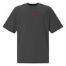 Front view of a oversized tee in faded black. A small red infinity-loop motif sits at the center chest as the only graphic — minimalist and restrained, with bold color contrast against the washed fabric.
