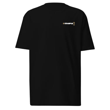 Front view of an t-shirt in black. A minimalist design placed on the upper left chest shows a compact arrangement of small graphic elements, including a circular icon, the word “KRAMPUS” in bold, and a narrow vertical block with stylized symbols.