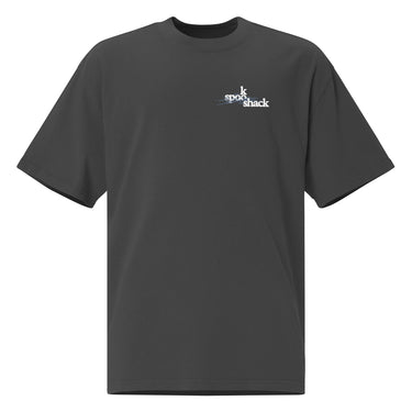 Front view of an oversized tee in black. Design features a small logo on the upper chest featuring the words "spook shack" in a stacked, stylized font, with abstract horizontal brush strokes layered behind the text.
