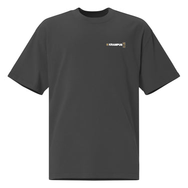 Front view of an oversized tee in black. A minimalist design placed on the upper left chest shows a compact arrangement of small graphic elements, including a circular icon, the word “KRAMPUS” in bold, and a narrow vertical block with stylized symbols.