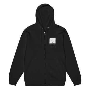 Front view of a zip hoodie in black. A small halftoned panel sits on the left chest: a bare, leafless tree standing over dark undergrowth, printed with a woven fabric texture and rough torn edges. Below it the words "pas seul" are set in a fine serif, the letters scattered and stepping down to the right.