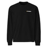 Front view of an longsleeve in black. A minimalist design is placed on the upper left chest, featuring a compact arrangement of graphic elements. The word “KRAMPUS” appears in small white uppercase lettering, paired with a circular gold icon to its left. 