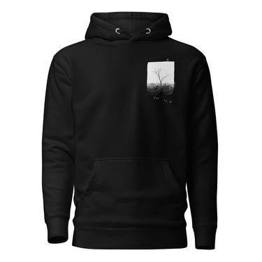 Front view of a hoodie in black. A small halftoned panel sits on the left chest: a bare, leafless tree standing over dark undergrowth, printed with a woven fabric texture and rough torn edges. Below it the words "pas seul" are set in a fine serif, the letters scattered and stepping down to the right.