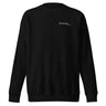 Front view of an sweatshirt in black. Design features a small, minimal text print placed on the upper left chest. The word “demiurge” appears in a clean serif font, preceded by a small infinity-shaped symbol. Just beneath it, in tiny handwritten script, the phrase “the mind” is printed in quotation marks.