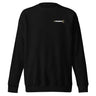 Front view of an sweatshirt in black. A minimalist design placed on the upper left chest shows a compact arrangement of small graphic elements, including a circular icon, the word “KRAMPUS” in bold, and a narrow vertical block with stylized symbols.