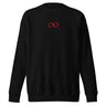 Front view of a sweatshirt in black. A small red infinity-loop motif sits at the center chest as the only graphic — minimalist and restrained, with bold color contrast against the dark fabric.
