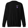 Front view of a sweatshirt in black. A small graphic sits high on the left chest: a loose, hand-drawn halo ring in white tilted above a sharp six-pointed star in soft violet. Both shapes print flat, the ring's brushed edges left rough and unfinished.