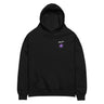 Front view of an oversized hoodie in black. A small graphic sits high on the left chest: a loose, hand-drawn halo ring in white tilted above a sharp six-pointed star in soft violet. Both shapes print flat, the ring's brushed edges left rough and unfinished.