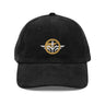 Front view of a corduroy cap in Black. A circular emblem is embroidered on the front panel: a plain gold ring, with a white winged spearhead stitched through its centre and swept wings running out to either side. Unstructured six-panel corduroy crown, curved brim, metal buckle.