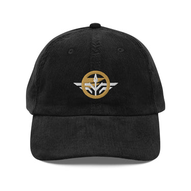 Front view of a corduroy cap in Black. A circular emblem is embroidered on the front panel: a plain gold ring, with a white winged spearhead stitched through its centre and swept wings running out to either side. Unstructured six-panel corduroy crown, curved brim, metal buckle.