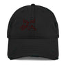Front view of a solid-colored, distressed hat. The front features an embroidered graphic composed of an abstract cluster of high-contrast, angular shapes.